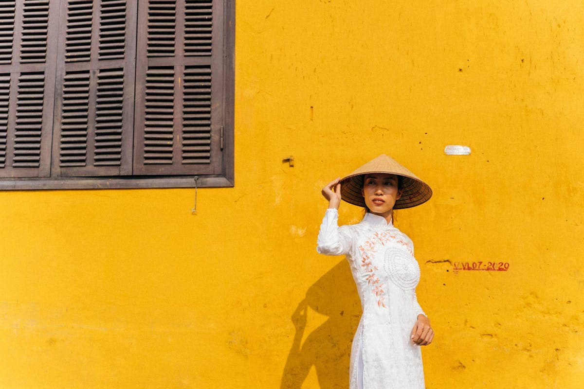 Family wearing traditional Vietnamese ao dai posing in front of the yellow heritage walls of Hoi An Old Town for a photoshoot