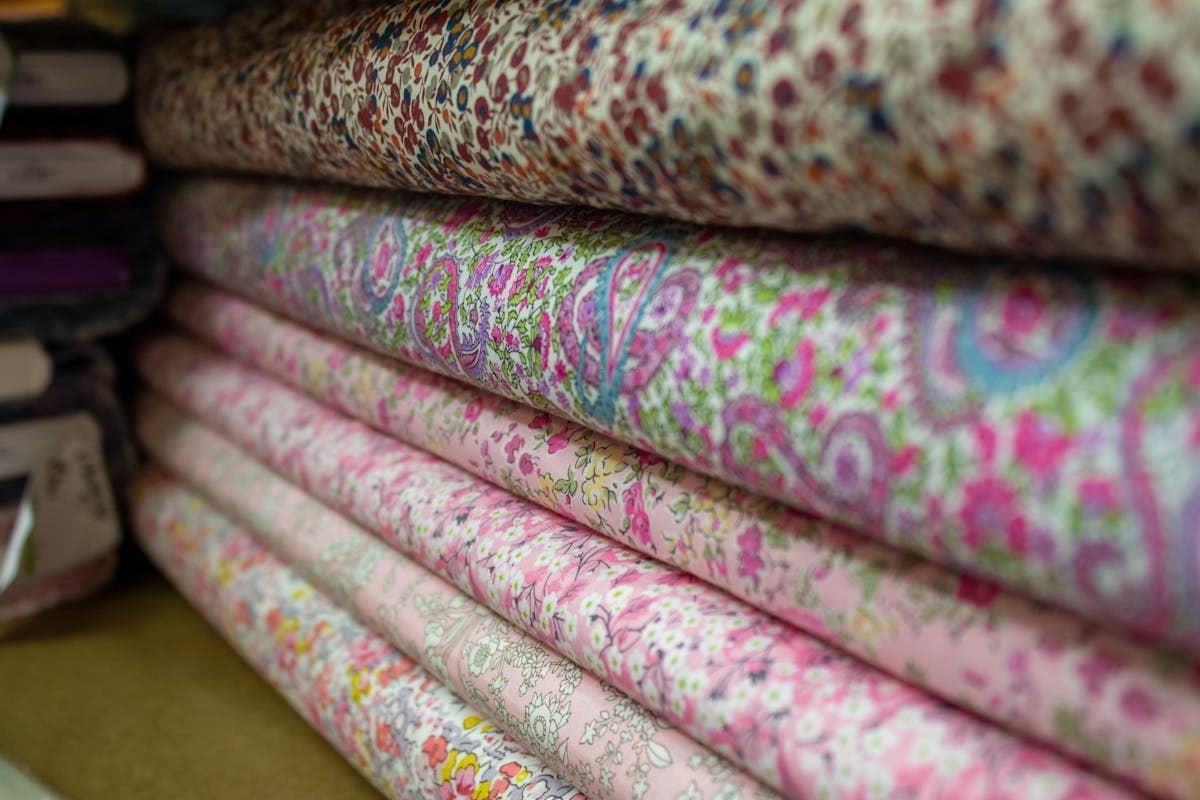 Rolls of colorful suiting and silk fabric stacked in a Hoi An tailor shop, ready for clients to browse