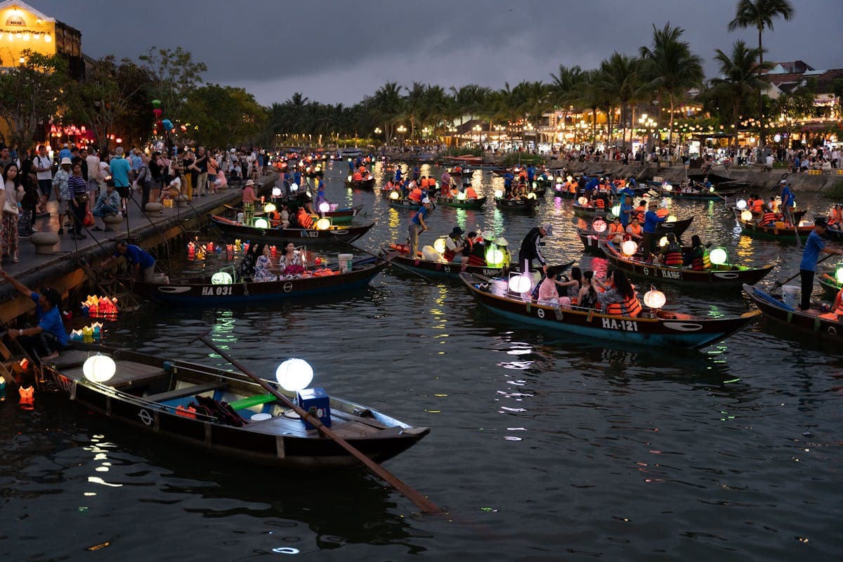 Hoi An Vietnam ancient town at dusk with glowing silk lanterns over a narrow heritage street lined with tailor shops, the UNESCO trading port that has been a textile and tailoring center since the 1600s