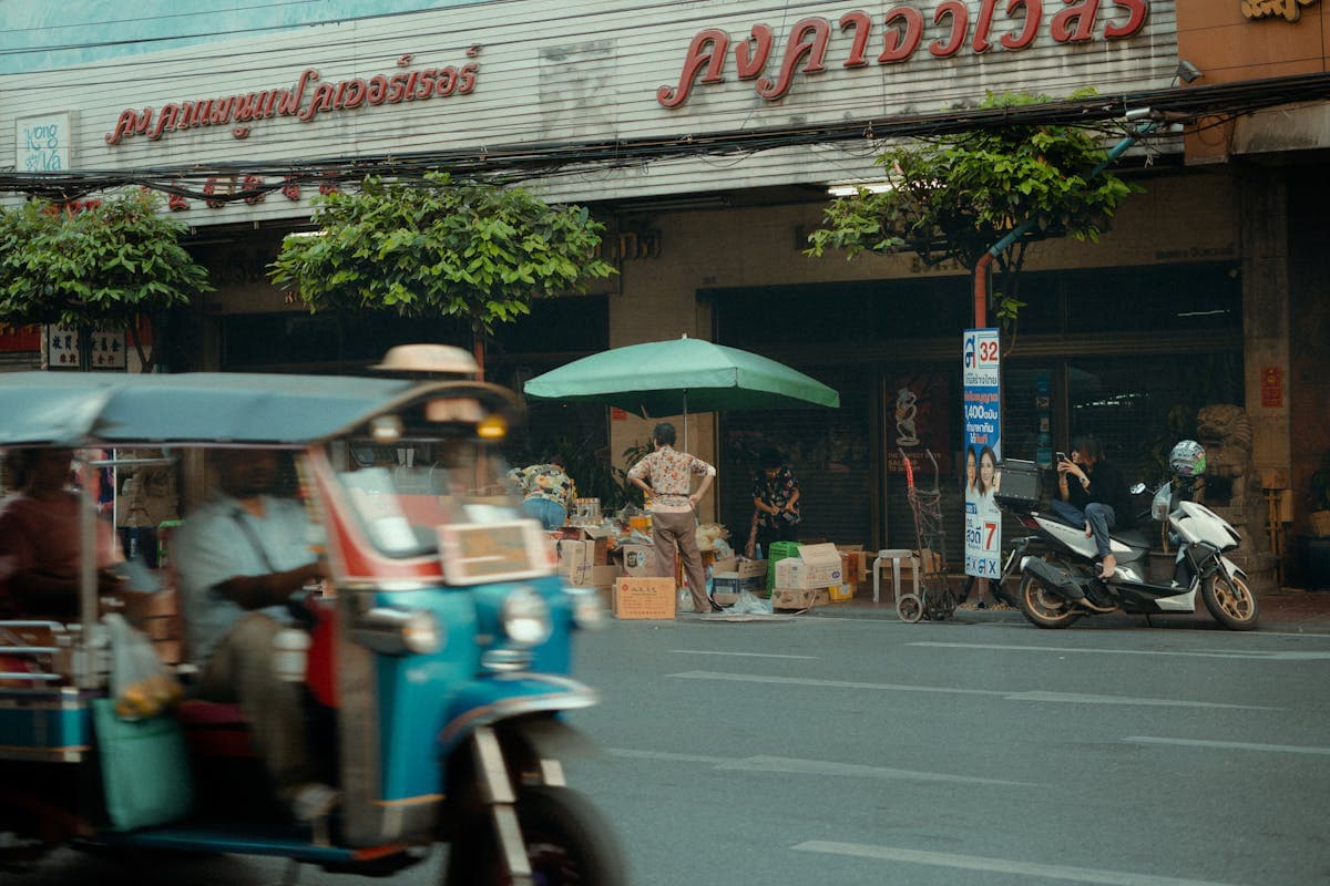 A tuk-tuk parked on a busy Bangkok street lined with shops along Sukhumvit