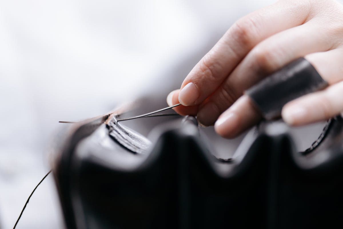 Close-up of hands hand-stitching a jacket lapel with needle and thread