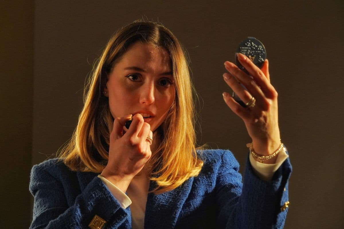 A young woman applying makeup at a mirror while getting ready for an event