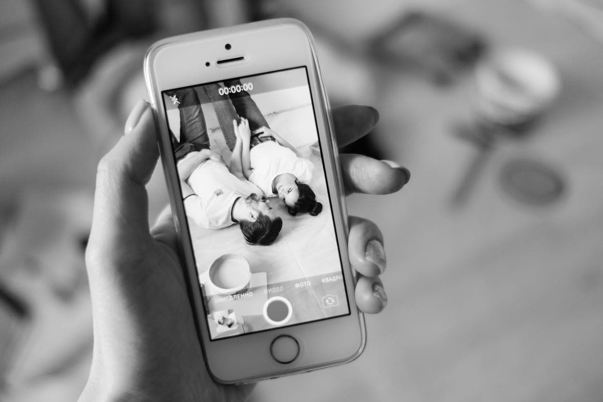 Someone taking a portrait photo of a dressed-up couple with a smartphone in golden light