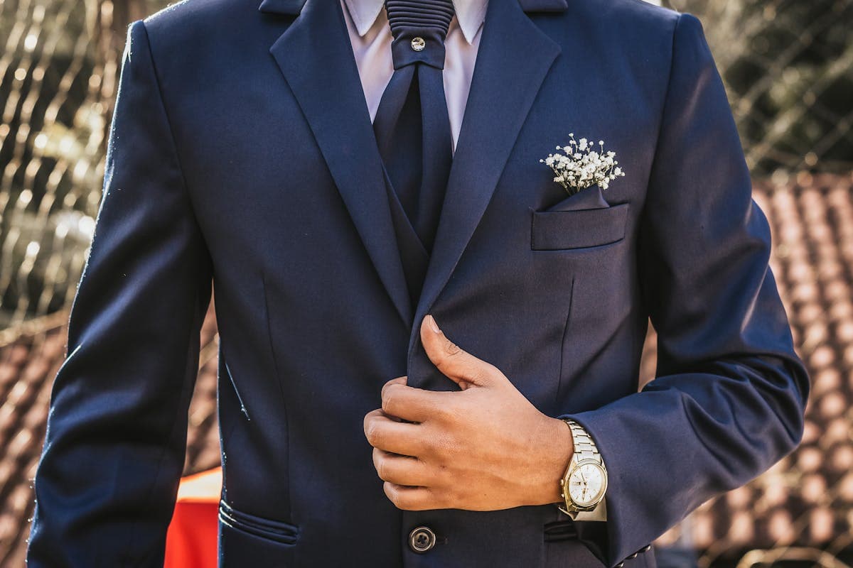 A confident young man wearing a well-fitted navy suit and tie