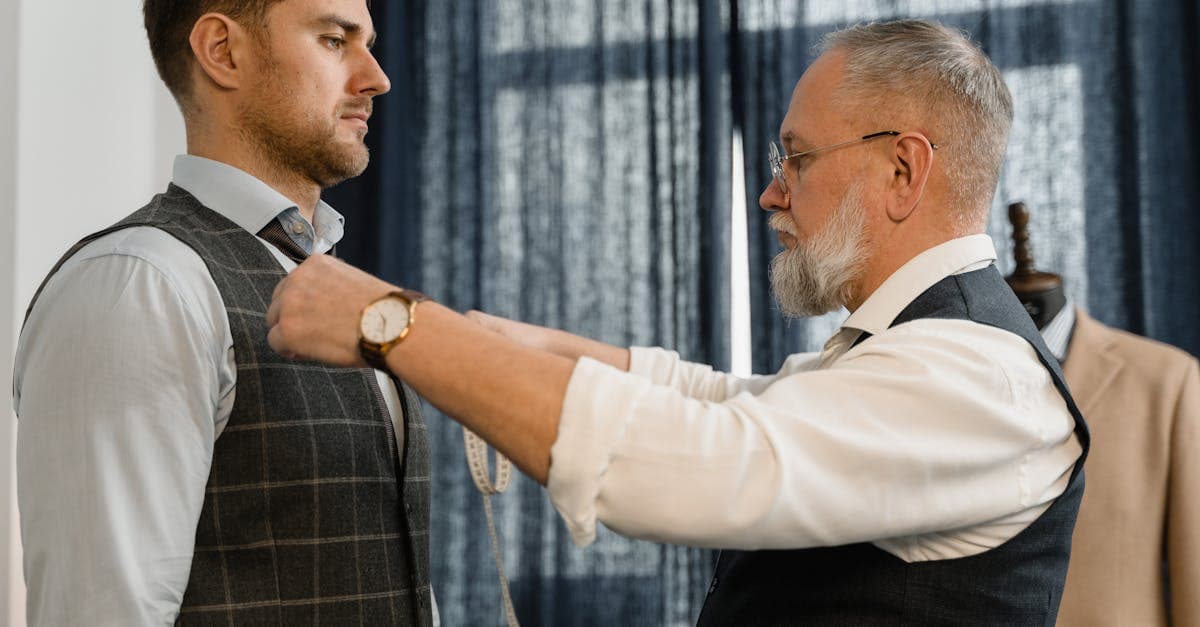 Man checking suit fit in a mirror at a tailor shop, examining shoulder line and jacket drape
