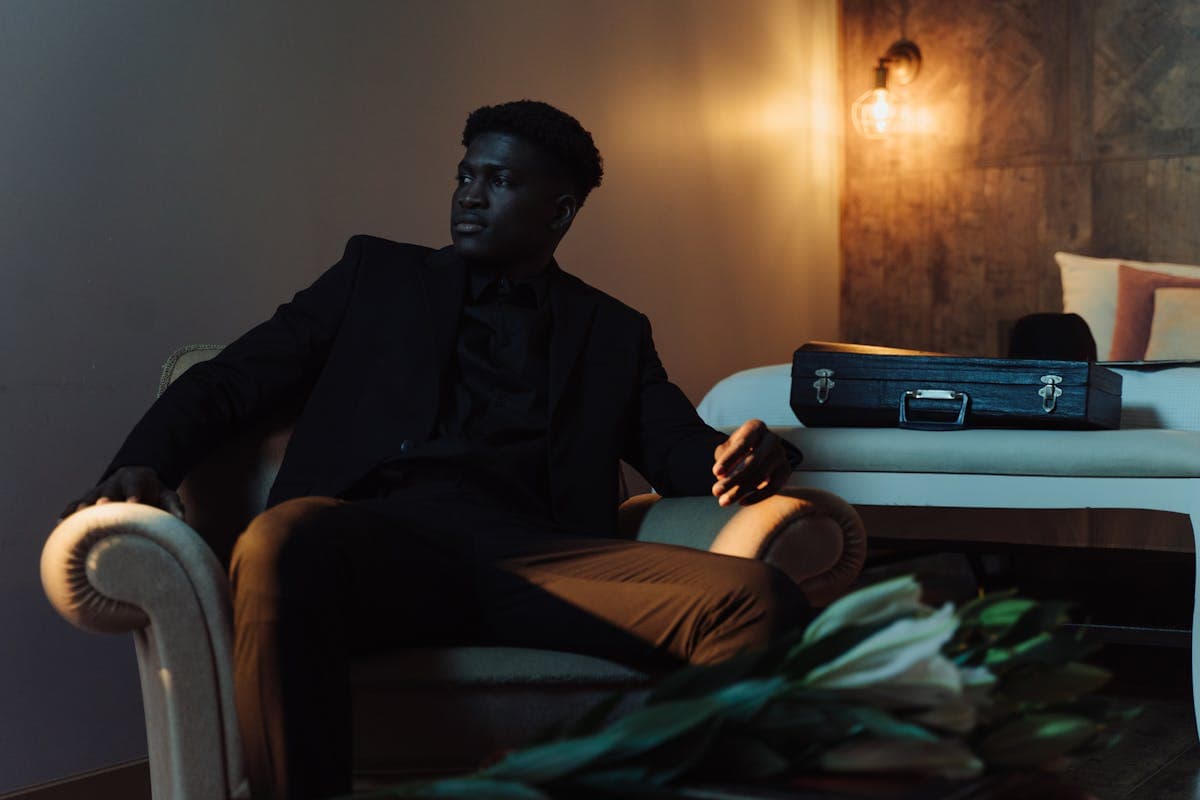 Young man in a deep green velvet blazer and tailored trousers posing confidently at a formal event