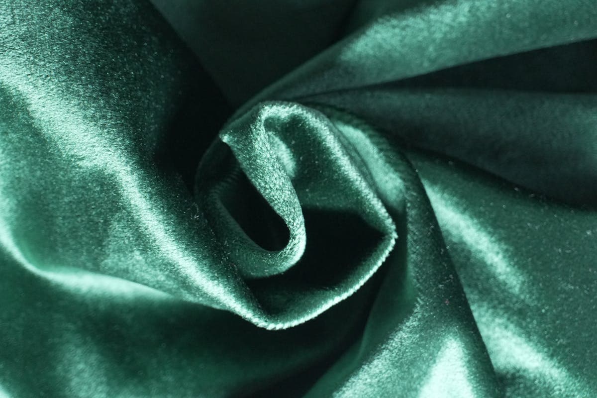 Close-up of rich velvet and brocade fabric folds in jewel tones catching the light