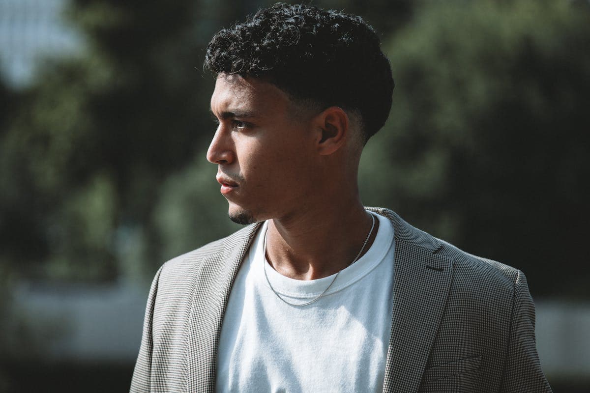 Man in a fitted camp collar shirt layered under a light unstructured blazer in warm weather