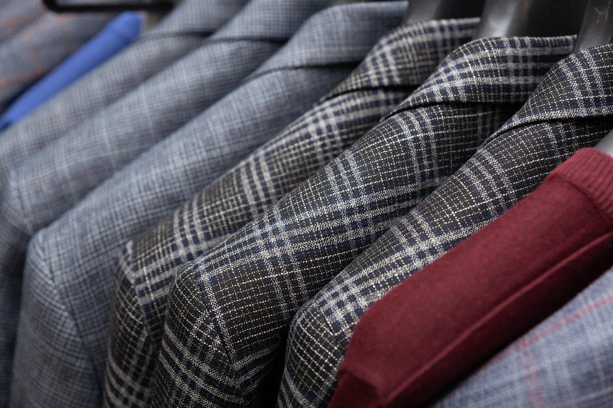 Finished tailored suit jackets hanging on a rail in a tailor's workshop