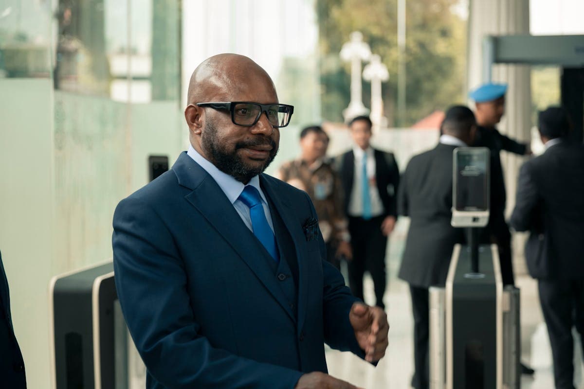Polished young professional in a solid navy suit and white shirt walking through a glass office lobby