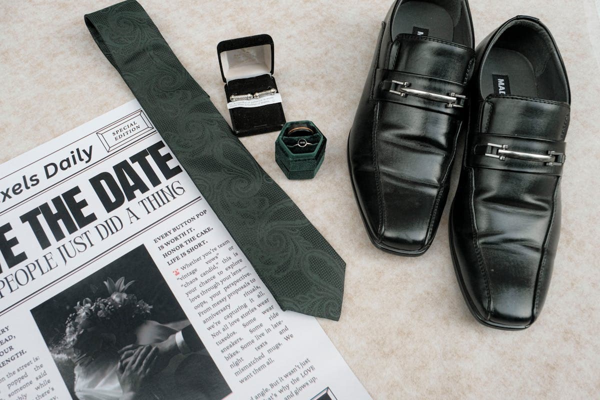 Flat lay of interview wardrobe essentials including a folded navy suit, white dress shirt, brown leather shoes, belt and tie