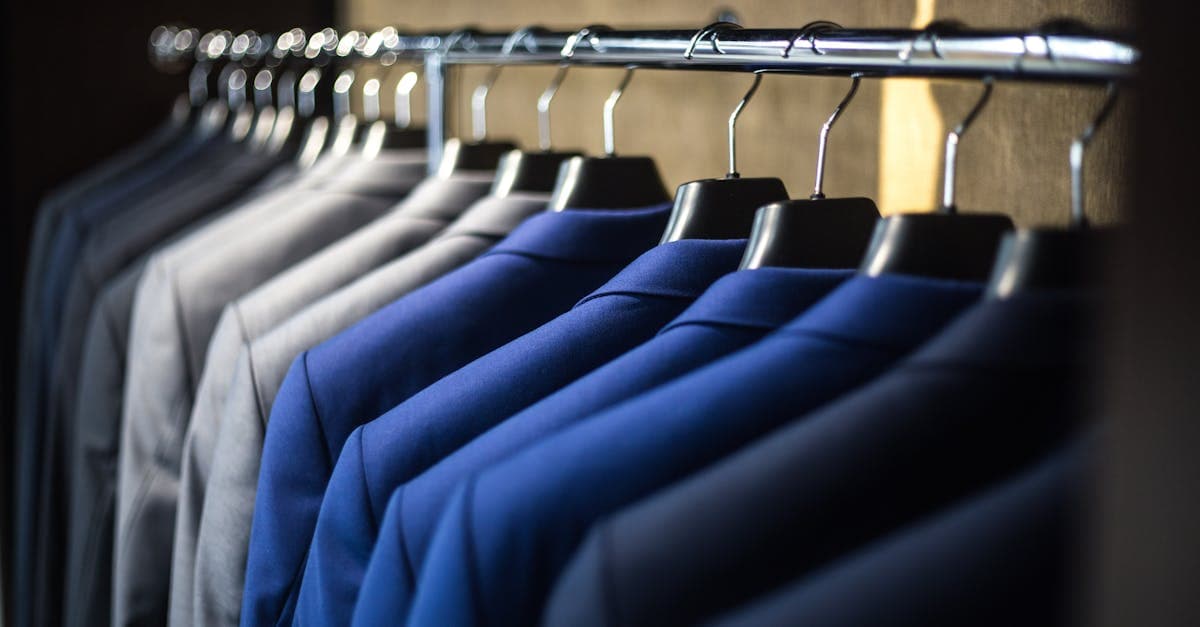 Rack of charcoal and navy men's suits in a traditional menswear store
