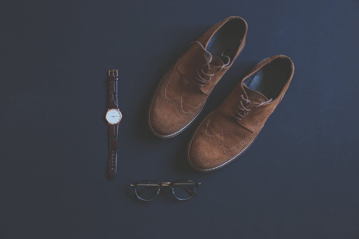 Flat-lay of a complete Kentucky Derby men's outfit — straw hat, pastel jacket, bow tie, pocket square, sunglasses and brown loafers laid out for Derby day