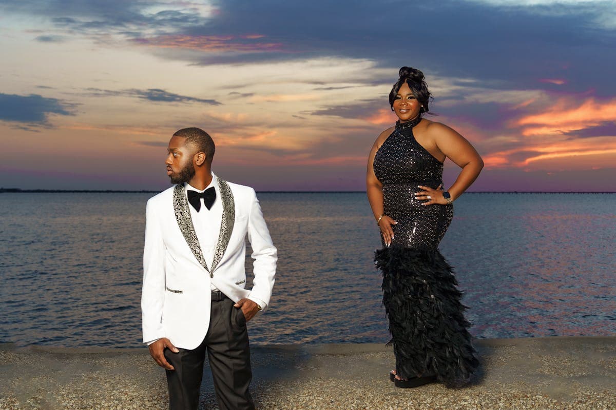 Couple in an all-black formal look, black suit and black dress, photographed like a movie premiere