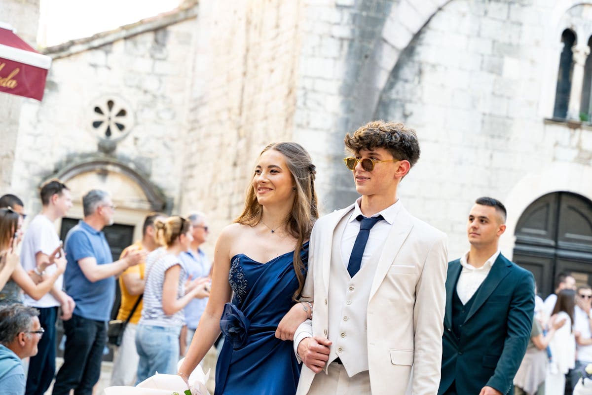 Well-dressed prom couple in coordinated formalwear, navy suit with an accent tie beside a jewel-tone gown