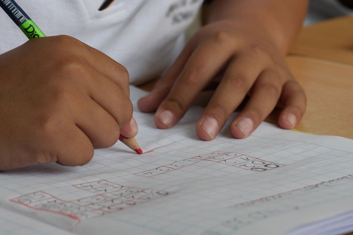 Hand writing measurements in a small notebook next to a coiled tape measure