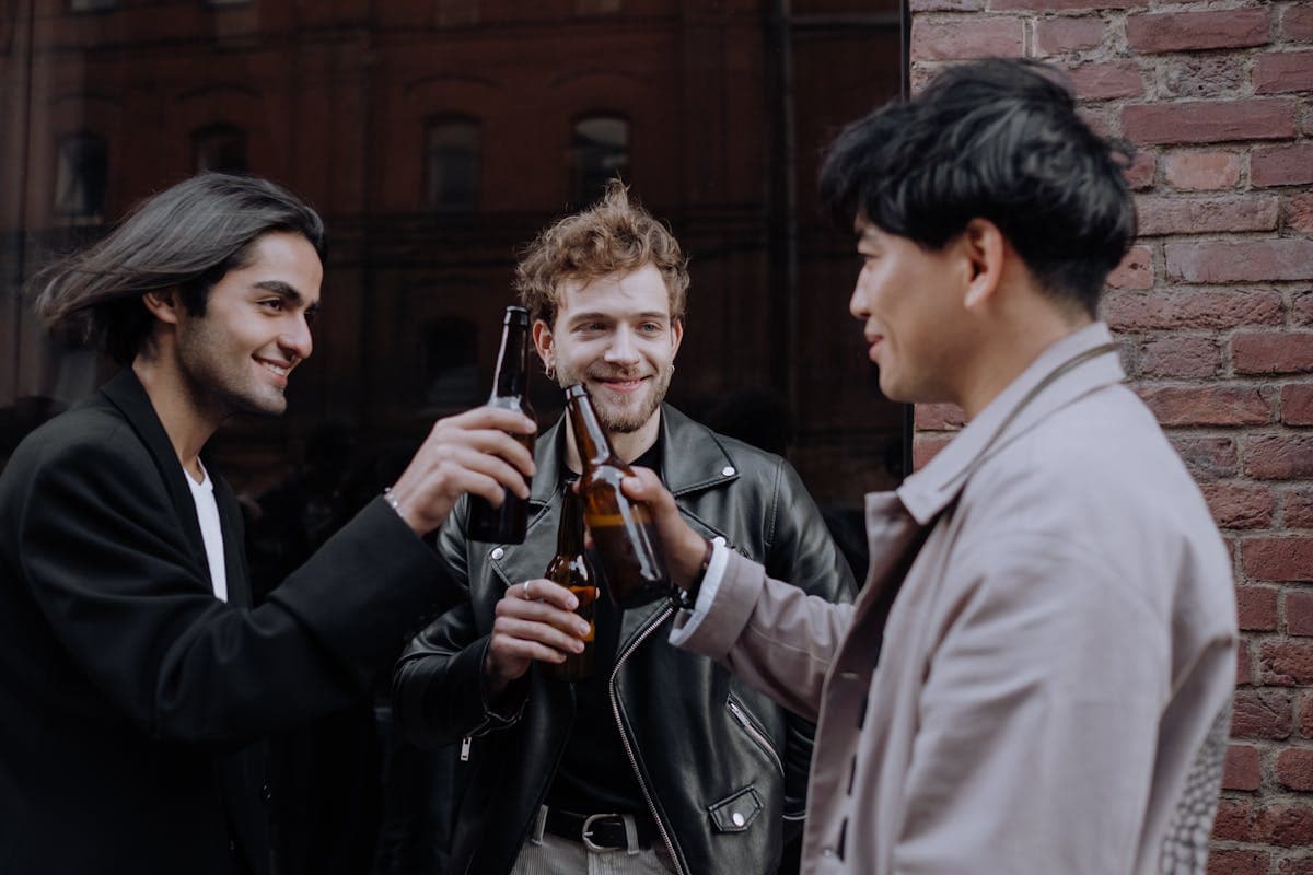 Group of male friends laughing and toasting drinks together on a trip, the boys-trip crowd that ends up getting suits made in Hoi An