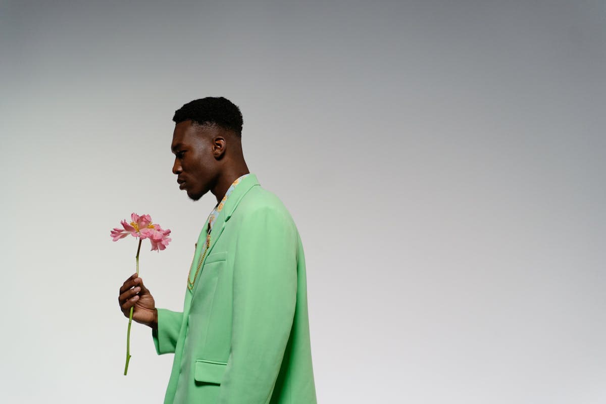 Man in a sage green earth-toned suit standing against a neutral backdrop