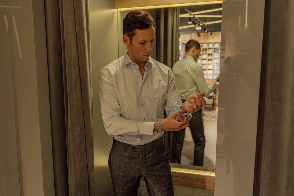 Man in a well-fitted suit checking his reflection in a fitting-room mirror