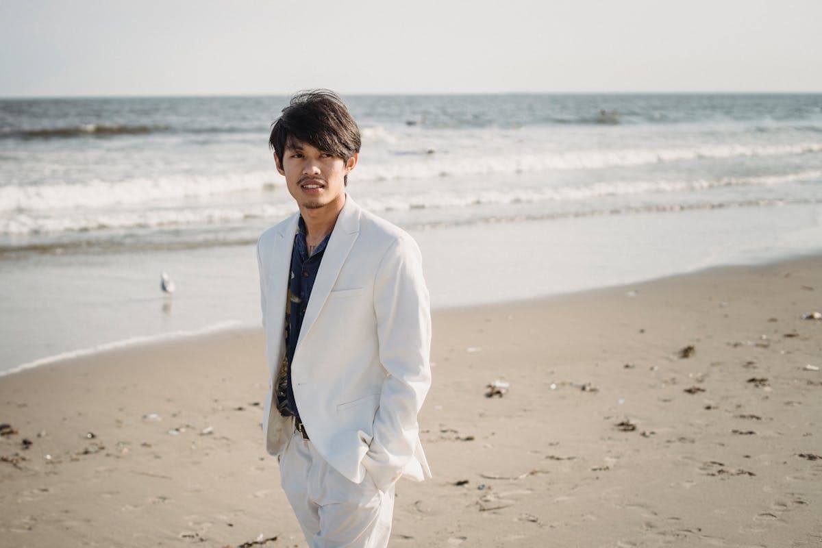 Man wearing a sharp all-white or cream suit outdoors in natural light, showing the monochromatic statement-piece look