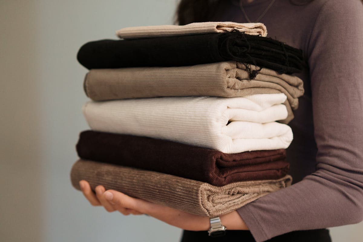 Stacks of suiting fabric bolts and swatches in rich colors, the kind of fabric library a custom suit consultation walks through