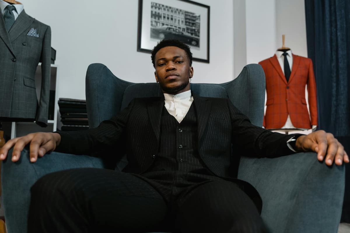 A single-breasted black wool suit with a notch lapel and a red armband on the left sleeve, laid flat on a tailor's cutting table