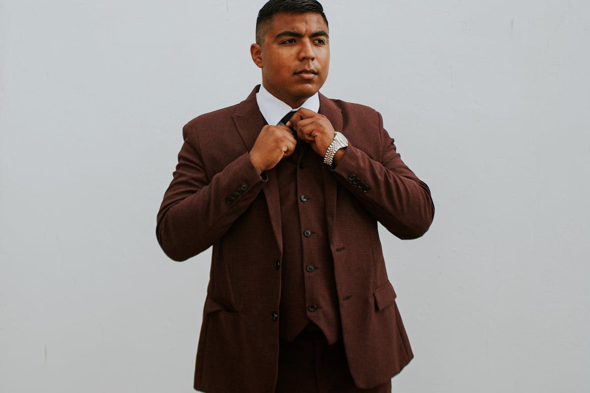 A man in a deep burgundy peak-lapel blazer with black trousers and a black tie, the tailored translation of the Thriller look