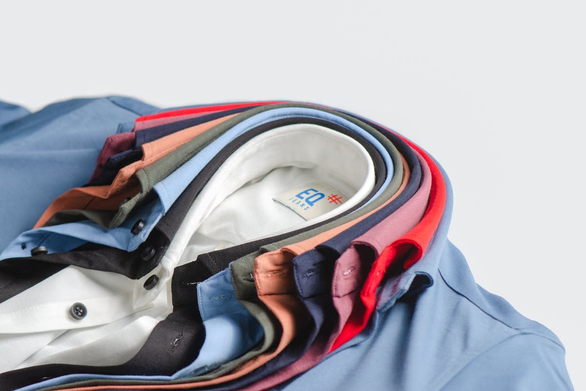Stack of crisply folded white and light-blue custom dress shirts on a tailor's worktable