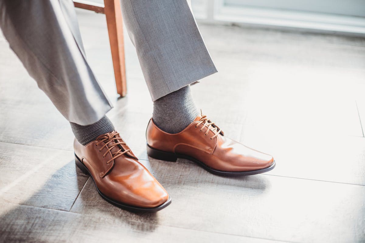 Close-up of well-tailored grey wool dress trousers breaking cleanly at the top of a leather dress shoe