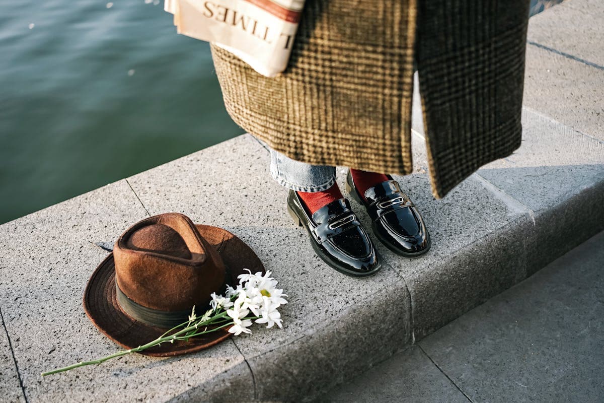 Black patent leather loafers worn with bright white socks showing at the ankle below dark trousers