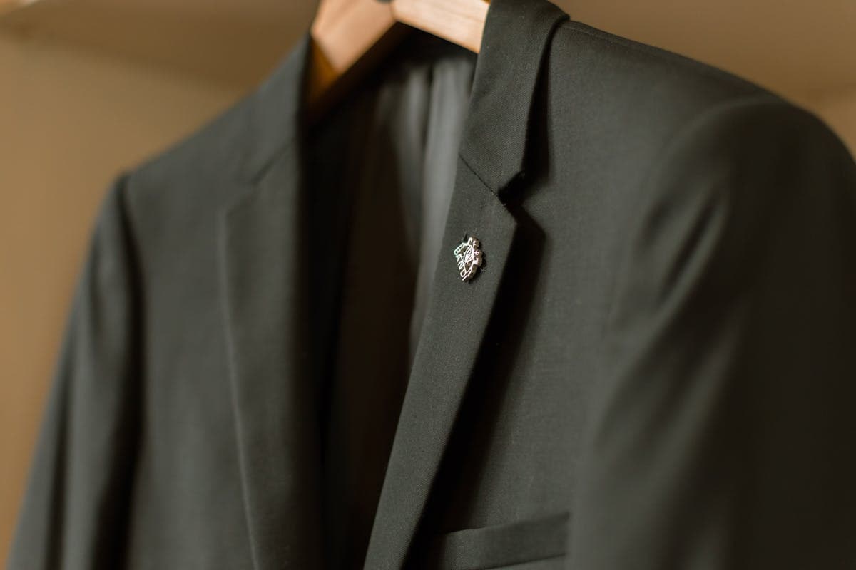 Close-up of a black single-breasted wool suit jacket showing the notch lapel, two-button stance, and clean shoulder line