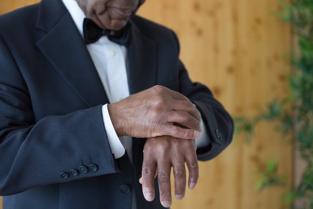 Close-up of a man adjusting the sleeve and cuff of a dark suit jacket, dressed and ready to head out for an evening screening
