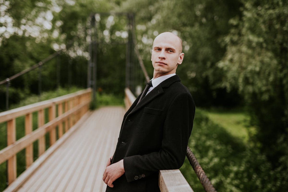 Close portrait of a man in a collarless band-collar suit with no tie, showing the clean line from throat to chest