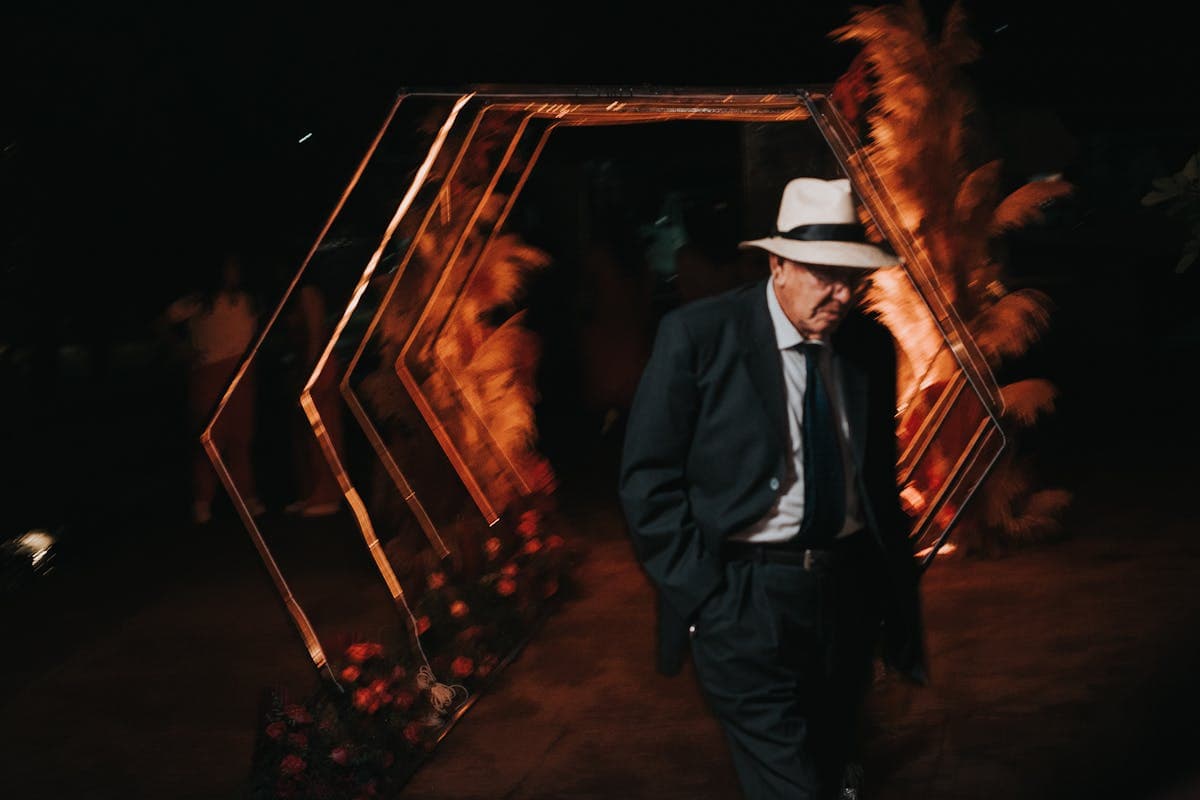 Well-dressed man in a dark band-collar suit at an evening event with soft warm lighting