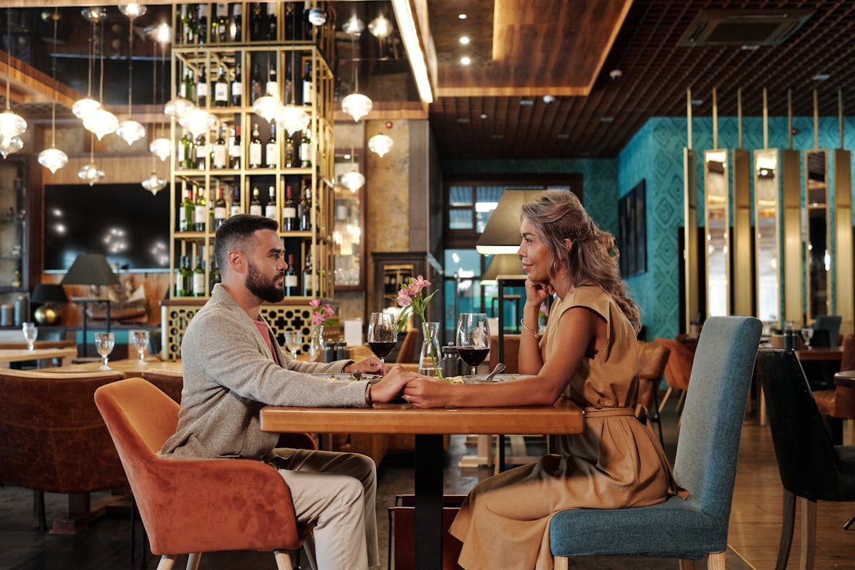 Man in a sharp blazer sharing a candlelit dinner with a date at a warmly lit New York restaurant