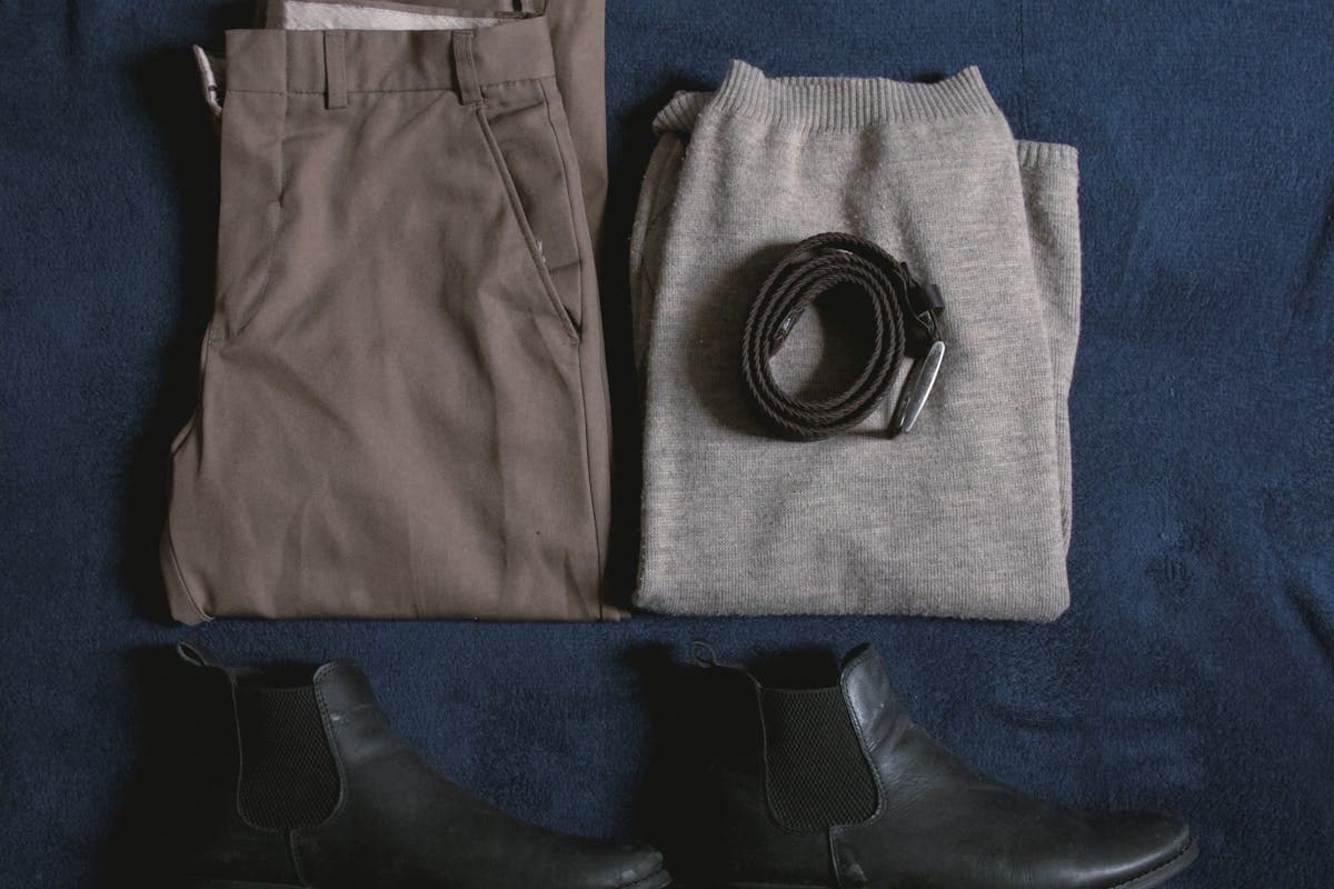Curated flat lay of a navy suit, charcoal blazer, white and blue dress shirts, and grey trousers