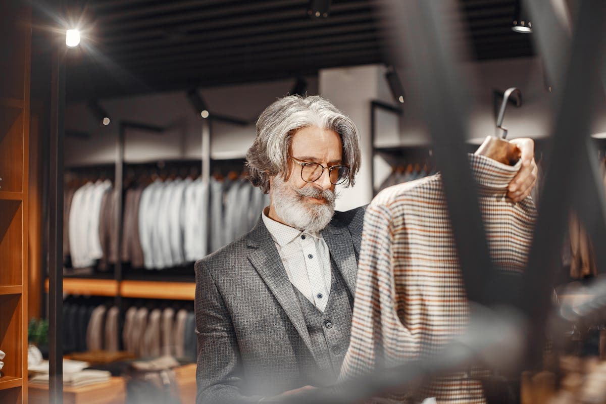 Suits hanging on a rack inside an upscale menswear store with visible price tags