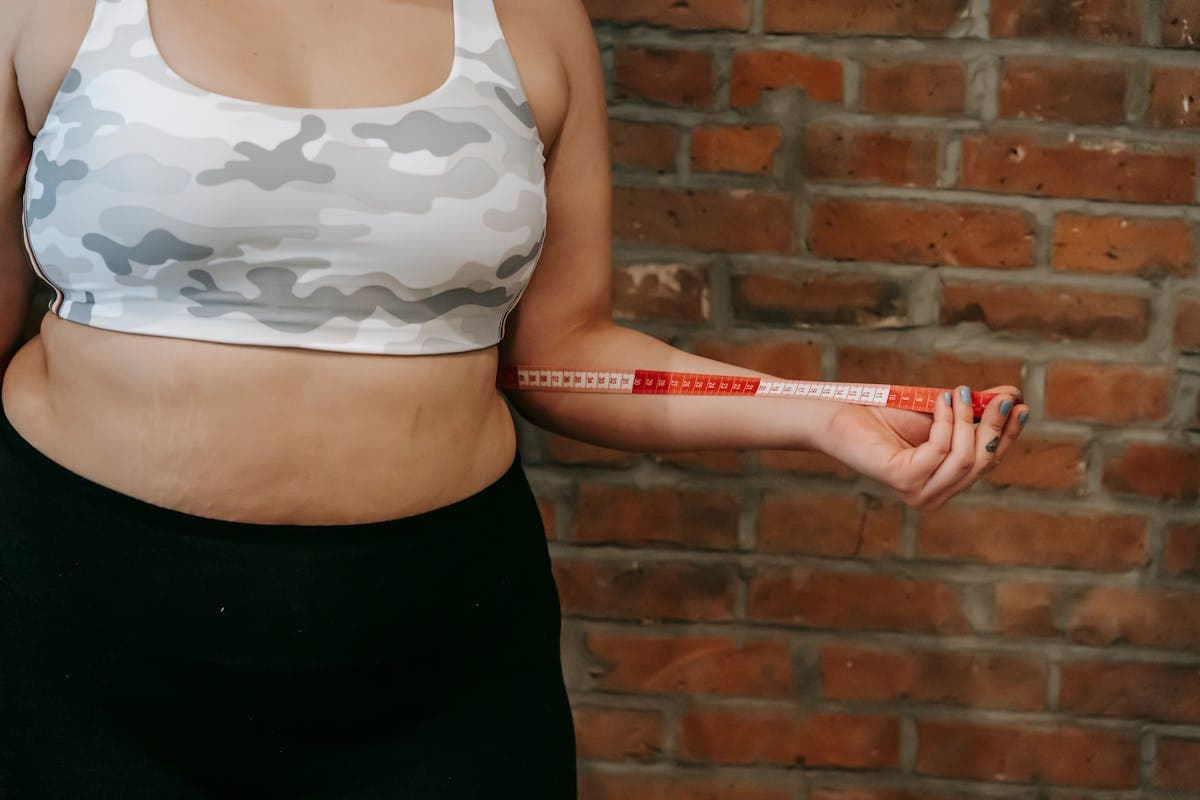 Person measuring their own chest with a tape measure at home next to a phone