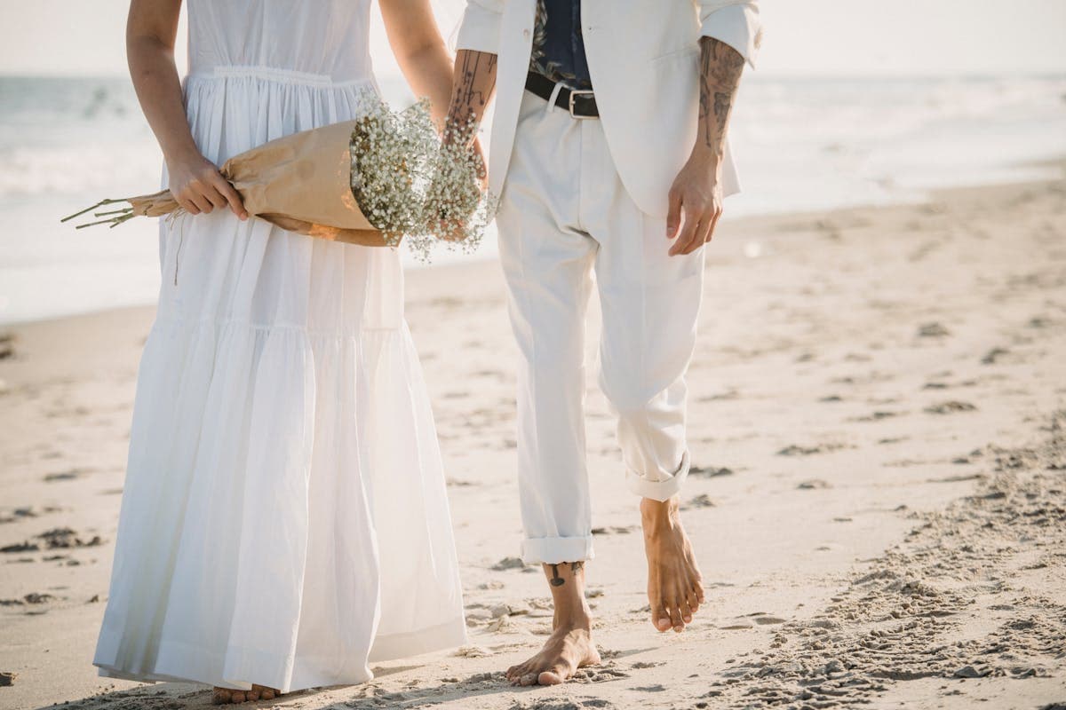 Man in a light tan linen suit with loafers at an outdoor seaside wedding