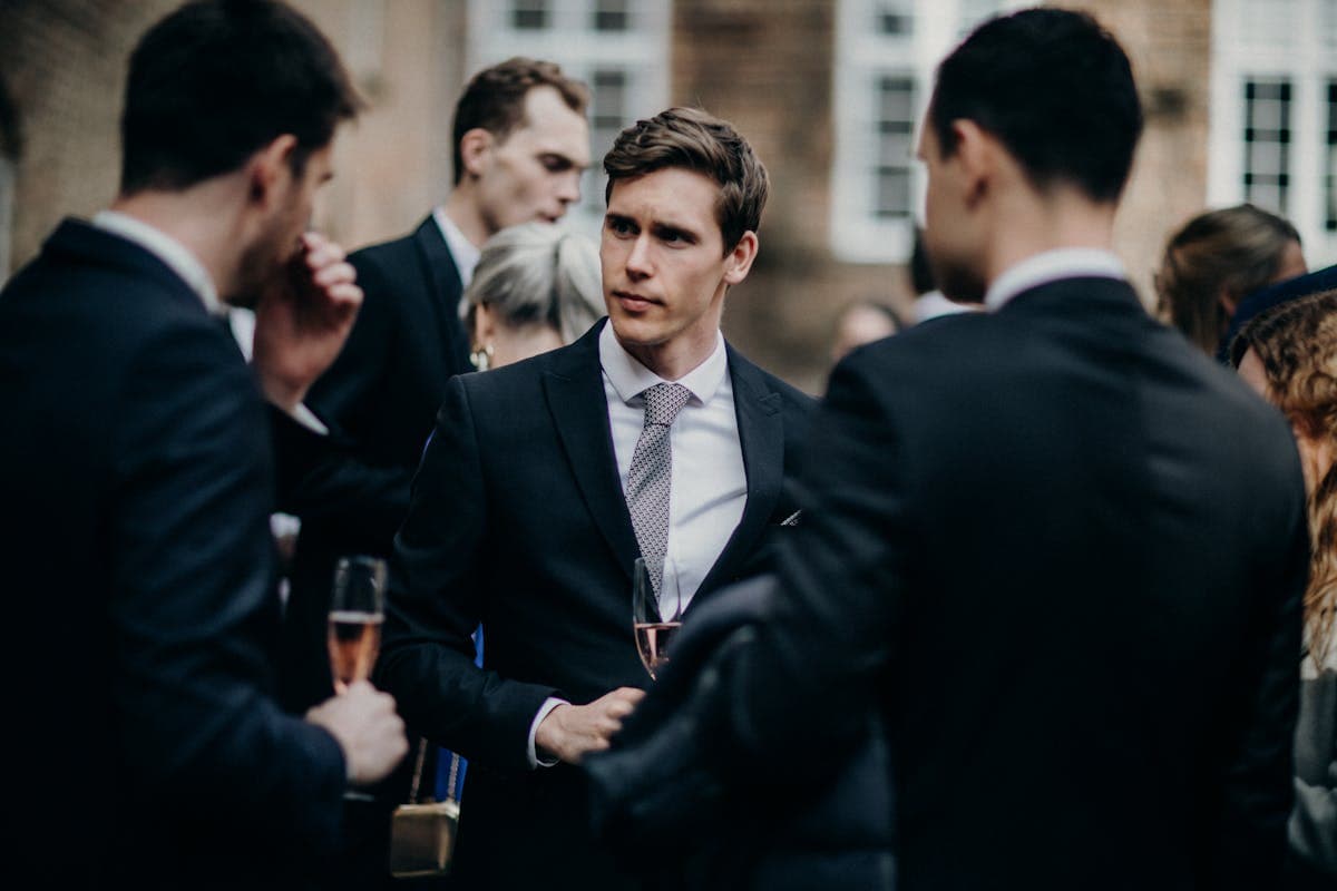 Man in a well-fitted navy suit with a knit tie at a summer wedding reception
