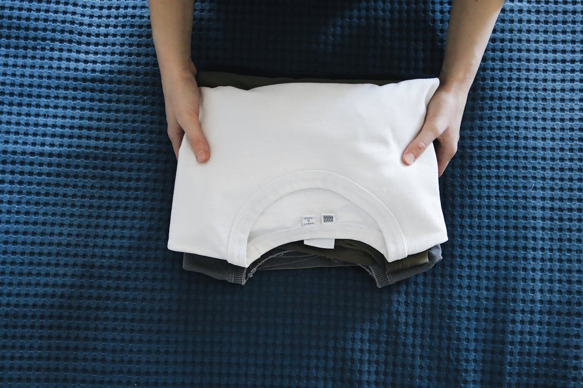 Flat lay of folded dress shirts in white and light blue beside grenadine and knit ties