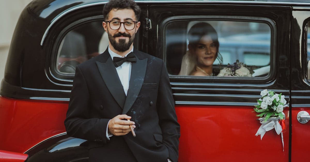 Groom in a navy worsted wool suit with a white silk pocket square standing on the steps of a stone country house, photographed in soft afternoon light