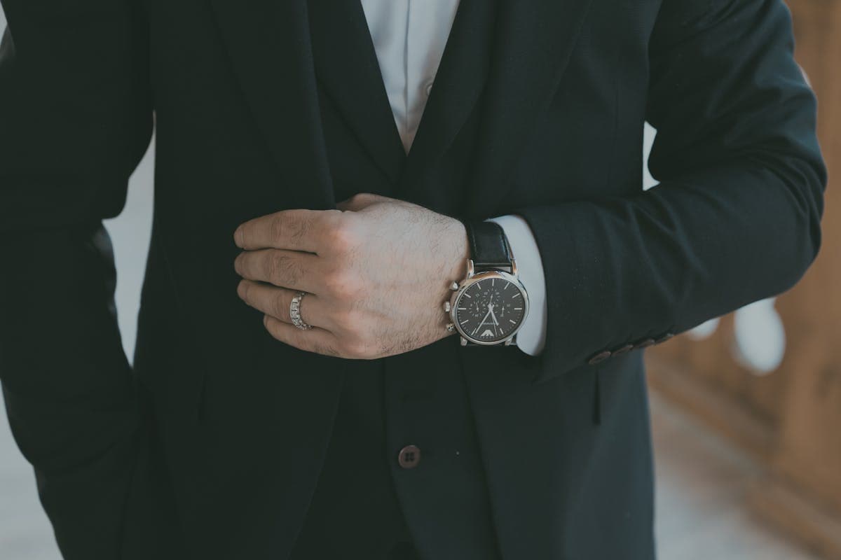 Close detail of a navy three-piece suit with peak lapel, white shirt and knit silk tie, no visible branding