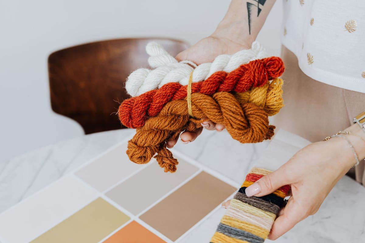 Man's hands resting on a fan of wool suit fabric swatches in greys and navies, deliberately choosing one