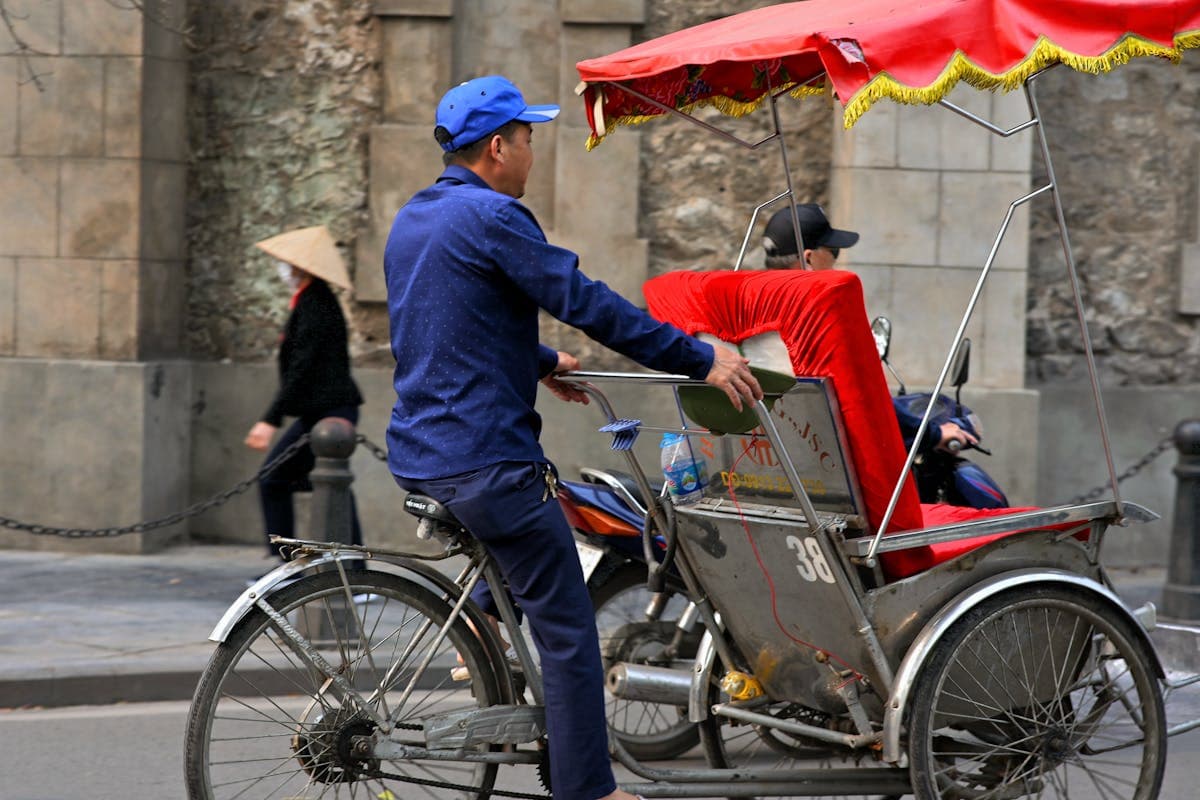 A cyclo driver waiting for passengers in Hoi An, Vietnam — one link in the local referral chain that routes visitors to tailor shops for a small finder's fee