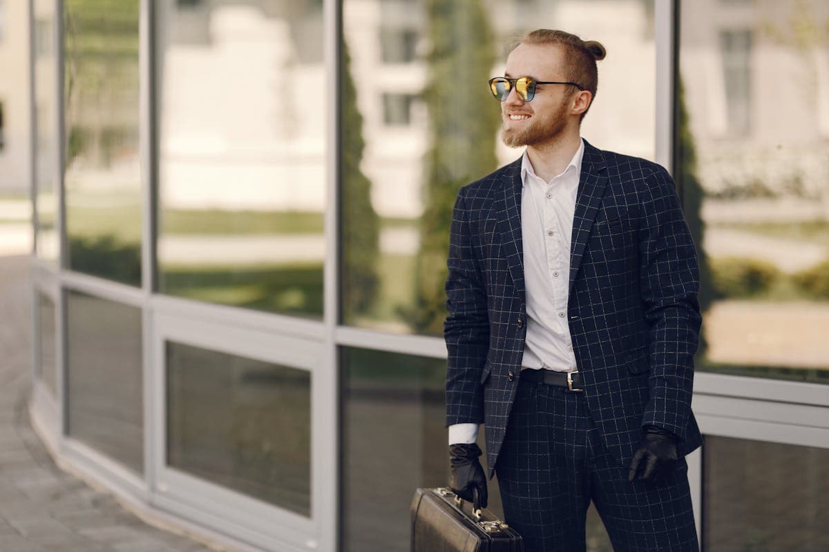 A well-dressed person in a sharply fitted custom suit standing confidently in a sunlit street