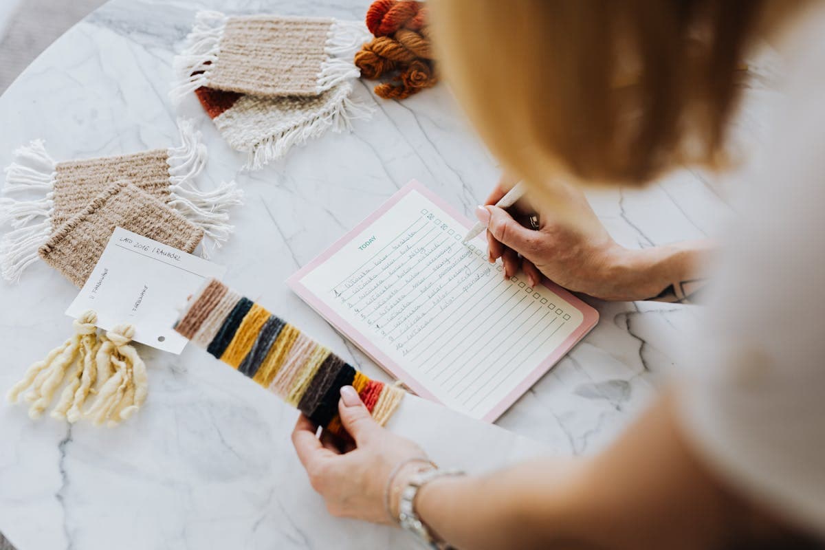 A hand examining folded fabric swatches in wool and linen, the kind a remote tailor mails before an order
