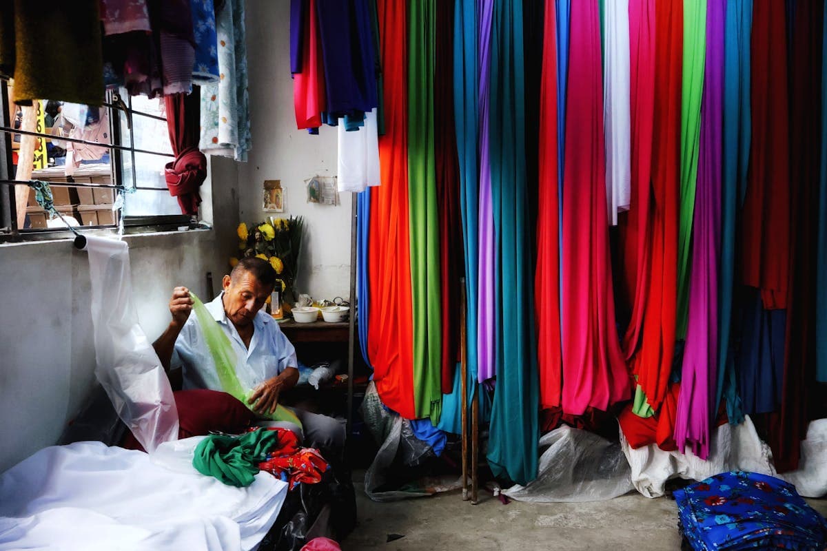Interior of a Hoi An Vietnam tailor shop with bolts of fabric on shelves and a sewing workspace