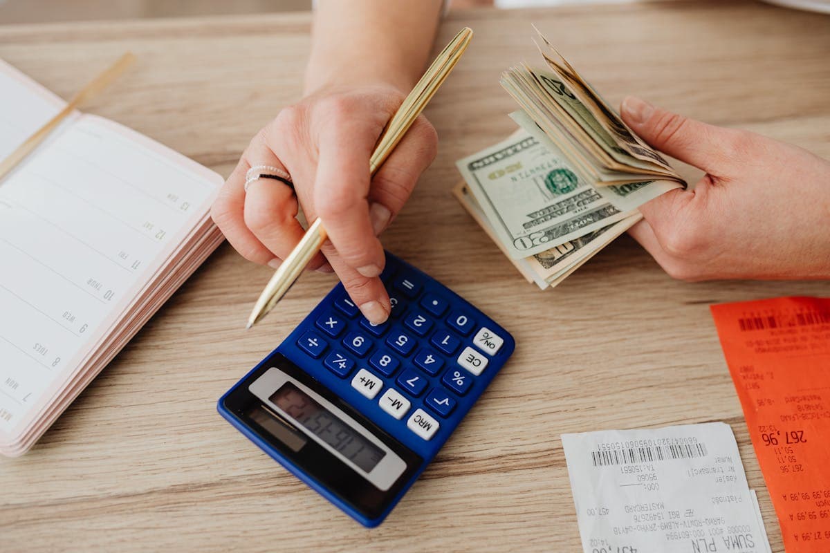 Hands with a calculator, notebook and tape measure laid out on a desk while planning a formal dress budget