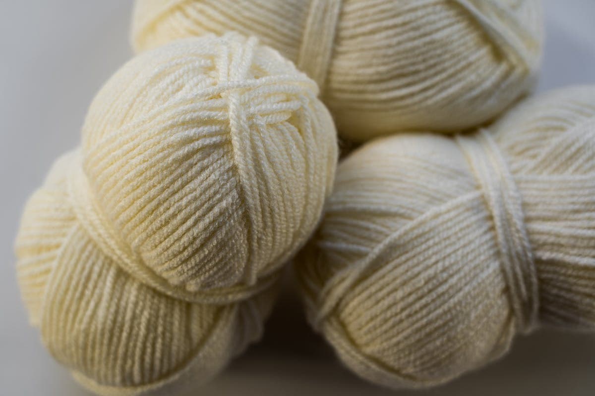 Close-up of ivory and cream wool suiting fabric showing warm tone and dense weave under soft light